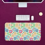 White desk mat with a colorful floral pattern featuring pink, orange, blue, and green flowers, designed for a unique workspace touch. Desk Pad with Keyboard and Mouse in pink background