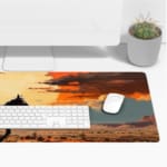 Silhouette of a rider on a horse with a sunset background, featuring dramatic orange and red clouds against a desert-like landscape. Desk Pad with Keyboard and Mouse on top of the desk pad