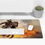 Desk pad with a rider on a brown horse amidst a fiery background with orange and yellow flames. Desk Pad with Keyboard and Mouse on top of the desk pad