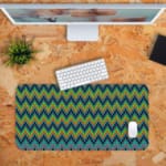 Infidu Desk Pad with a blue background featuring a zigzag knitted pattern in shades of blue, green, and yellow. Desk Pad with Keyboard and Mouse in orange background