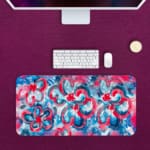 Infidu Desk Pad with vibrant pink and blue swirls, creating an energetic and eye-catching design. Desk Pad kept on a pink background