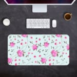 Light mint green desk mat with large pink roses and green leaves, offering a unique and charming touch to your workspace. Desk Pad Design Kept on a computer table