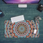 Infidu Desk Pad featuring intricate mandala design with blue background and vibrant orange, red, and white details. Design Kept on a computer table