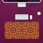 Infidu Desk Pad with bold mandala-like pattern and vibrant red, yellow, and orange details. Desk Pad kept on a pink background