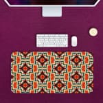 Infidu desk pad with an ornate floral pattern in orange, red, and cream on a light cream background, adding elegance to your workspace. Desk Pad kept on a pink background