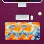 Infidu Desk Pad with an abstract blend of orange, blue, and white, resembling a sunset or colorful sky Desk Pad kept on a pink background