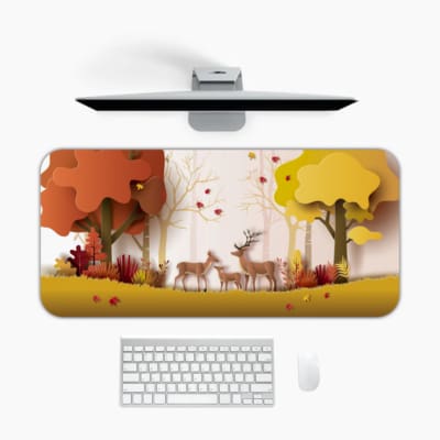 Infidu Explore Nature Desk Mat features a colorful nature scene with deer, autumn-colored trees, and falling leaves in yellow and red tones. Desk Mat with an Apple Computer