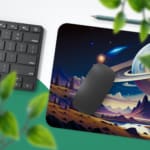 Infidu Space Desk Pad features an alien landscape with mountains, trees, a lake, and large planets on a dark blue night sky background. Desk Pad with Keyboard and Mouse