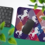 Unicorn Desk Mat with a white unicorn on a colorful background of green, yellow, navy blue, blue, and gray. Desk Pad with Keyboard and Mouse