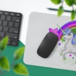 Unicorn Desk Mat with white background, rainbow, and purple stars, and a unicorn with a greenhorn surrounded by clouds. Desk Pad with Keyboard and Mouse