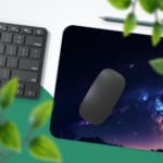 Infidu Space Desk Pad features a deep space view with a star cluster, nebulae, and a bright spot fading into dark blue and purple edges. Desk Pad with Keyboard and Mouse