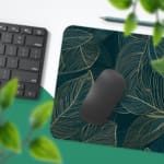 Green desk mat with outlined leaf patterns in yellow and green, featuring a unique and creative design by digital artists. Desk Pad with Keyboard and Mouse