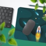 Infidu Space Desk Pad featuring a rocket launch, planets, and stars on a dark teal background. Desk Pad with Keyboard and Mouse