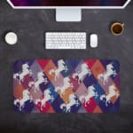 Unicorn Desk Mat with a white unicorn on a colorful background of green, yellow, navy blue, blue, and gray. Desk Pad with Design Kept on a computer table