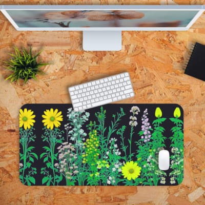 Black desk mat with colorful flower and plant illustrations, including yellow daisies and green plants, featuring a unique design. Desk Pad with Keyboard and Mouse in orange background