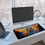 Colorful stained-glass insect design desk pad with vibrant tones and a dark background. A computer and laptop are next to the desk pad