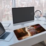 Fluffy white cat sitting in an elegant room with warm lighting, decorative flowers, and antique furniture. A computer and laptop are next to the desk pad