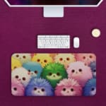 Infidu desk mat with colorful anime cats in pink, blue, and green, adding a vibrant touch to your desk setup. Desk Pad kept on a plain pink background