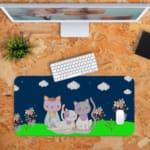 Infidu Bring Cat Magic Desk Mat featuring anime cats with a navy blue sky, clouds, and floral designs. Perfect for adding charm to any desk. Desk Pad kept on a plain orange background