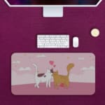 Infidu Bring Cat Magic Desk Mat featuring lovable cats and heart designs on a white background with clouds. Perfect as a desk mat, desk pad, or gaming pad. Desk Pad kept on a plain violet background