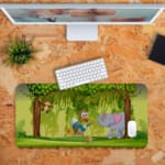 Infidu Explore Nature Desk Mat features a colorful forest scene with a bird, elephant, monkey, and a lively green and brown background. Desk Pad kept on a plain orange background