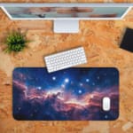 Infidu Space Desk Pad featuring a swirling nebula in orange, pink, and blue set against a starry space background. Desk Pad kept on a orange background