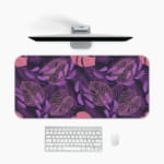 Stylized leaf patterns in lighter shades of purple and pink on the Infidu Bring the Beauty of Flowers Desk Mat with a computer