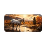 A white horse standing in a stream with a natural backdrop of golden-orange trees, mountains, and a sunset sky on a desk pad. Desk Pad kept on a plain white background