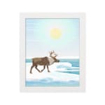 Christmas wall art featuring a reindeer walking on snow near a body of water with a bright sun and blue sky in the background. in plain white background in a white frame