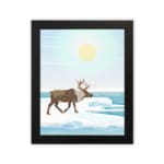 Christmas wall art featuring a reindeer walking on snow near a body of water with a bright sun and blue sky in the background. in plain white background in a black frame