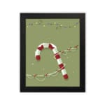 Candy cane with red and white stripes, surrounded by colorful Christmas lights on a light grey or muted green background with a plain white background in a black frame