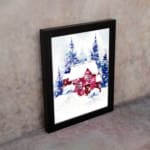 Christmas wall art featuring a pink house and blue pine trees in a watercolor style with a light background. on the wall in a black frame