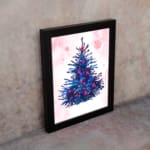 Pink stocking Christmas wall art with red accents, green leaves, berries, and a starry pink background. on the wall in a black frame