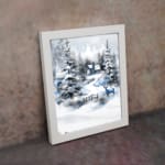 Infidu A Joyous Holiday Wall Art - Tranquil Winter Forest Scene with Deer shows a snowy forest with evergreen trees, a blue house, and a deer. displayed on the wall in white frame