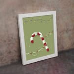 Candy cane with red and white stripes, surrounded by colorful Christmas lights on a light grey or muted green background. dismantle the wall in a white frame