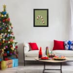 Candy cane with red and white stripes, surrounded by colorful Christmas lights on a light grey or muted green background. displayed on the wall in a black frame