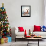 Winter-themed wall art with a reddish-brown deer, blue trees, and a light, snowy background in a watercolor style. displayed on the table in a black frame