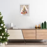 Christmas wall art featuring a white tree with red ornaments, gifts underneath, a reindeer, and a snowy background in a watercolor style. displayed on the floor