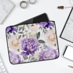 Elegant floral laptop sleeve with purple flowers and green leaves on a soft, light background. laptop sleeve kept on a plain white background