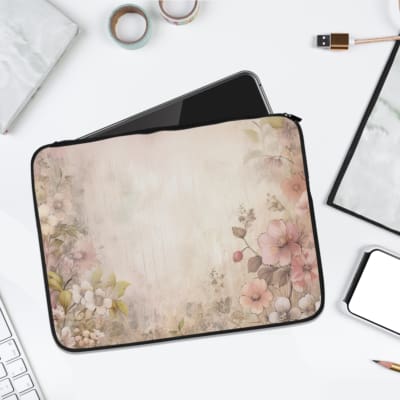 Soft beige laptop sleeve with delicate floral design in pink, green, and purple, featuring a zip closure for secure storage. laptop sleeve kept on a plain white background