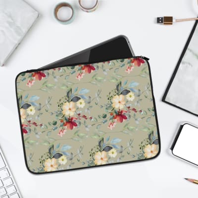 Gray laptop sleeve with white floral design, pink and green accents. laptop sleeve kept on a plain white background