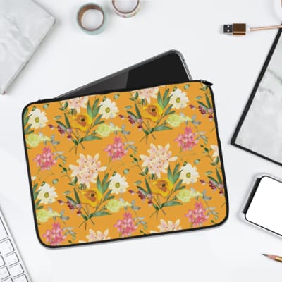 Laptop sleeve with yellow floral design, featuring pink, white flowers, and green leaves on a bright yellow background. laptop sleeve kept on a plain white background