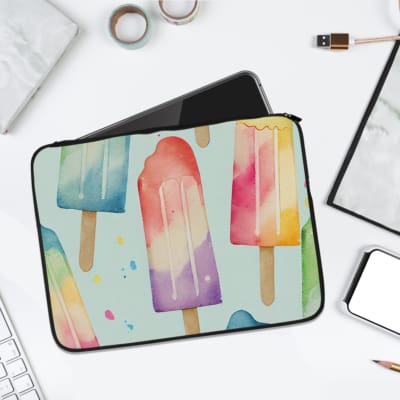 Laptop sleeve with pastel-colored popsicle design in blue, pink, purple, and peach on a light background with zip closure. laptop sleeve kept on a plain white background