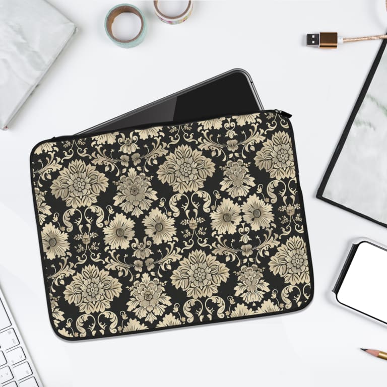 Laptop sleeve with elegant white floral and leaf motifs on a black background, featuring durable fabric and a secure zip closure. laptop sleeve kept on a plain white background