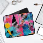 Laptop sleeve with a vibrant abstract design featuring blue, pink, purple, yellow, and black hues, secured with a zip closure. laptop sleeve kept on a plain white background