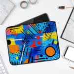 Laptop sleeve with a bright blue background featuring colorful abstract geometric shapes in yellow, pink, orange, black, and red, with zip closure. laptop sleeve kept on a plain white background