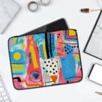 Laptop sleeve with a vibrant abstract design featuring shapes, lines, and patterns in blue, pink, yellow, and black. laptop sleeve kept on a plain white background