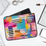 Infidu Bold Abstract Laptop Sleeve featuring bright geometric patterns in pink, blue, yellow, black, and white with a secure zip closure. laptop sleeve kept on a plain white background