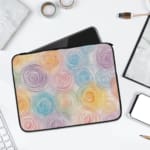 Laptop sleeve with a circular swirl pattern in pastel colors, including blue, pink, purple, yellow, and orange on a white background. laptop sleeve kept on a plain white background