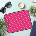 Pink laptop sleeve with a repeating white star pattern, shown against a bright background. the laptop sleeve on the table